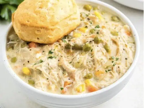 bowl of chicken pot pie topped with a biscuit.